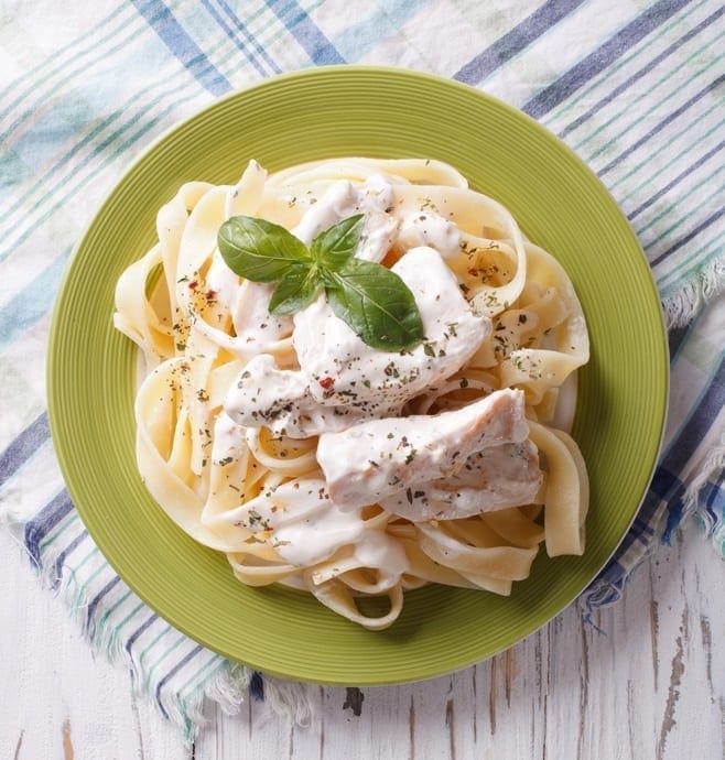 Chicken Alfredo Fettuccine in cream sauce on a plate. vertical top view